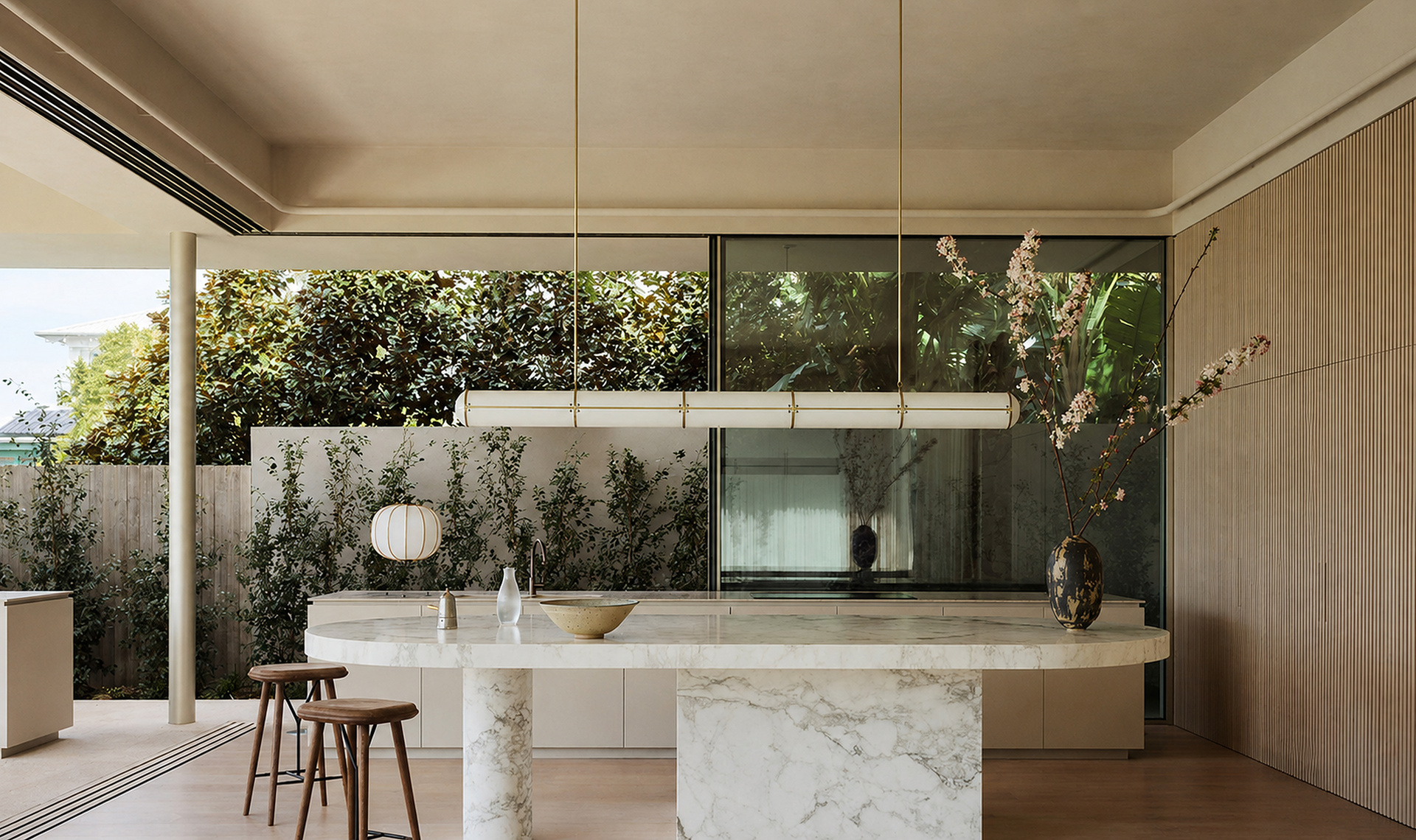 Open marble kitchen with timber stools and garden views in an Australian coastal villa