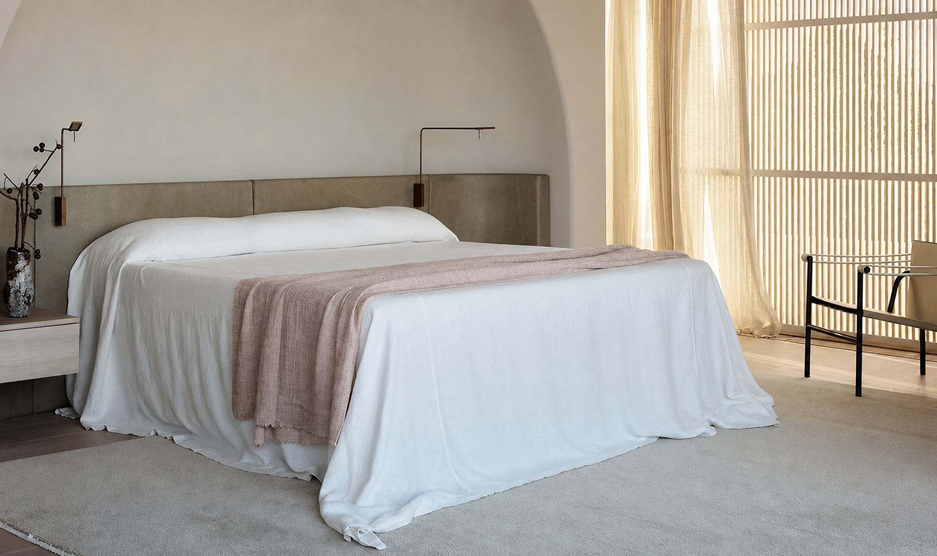 Calm principal bedroom with an arched wall and soft neutral furnishings