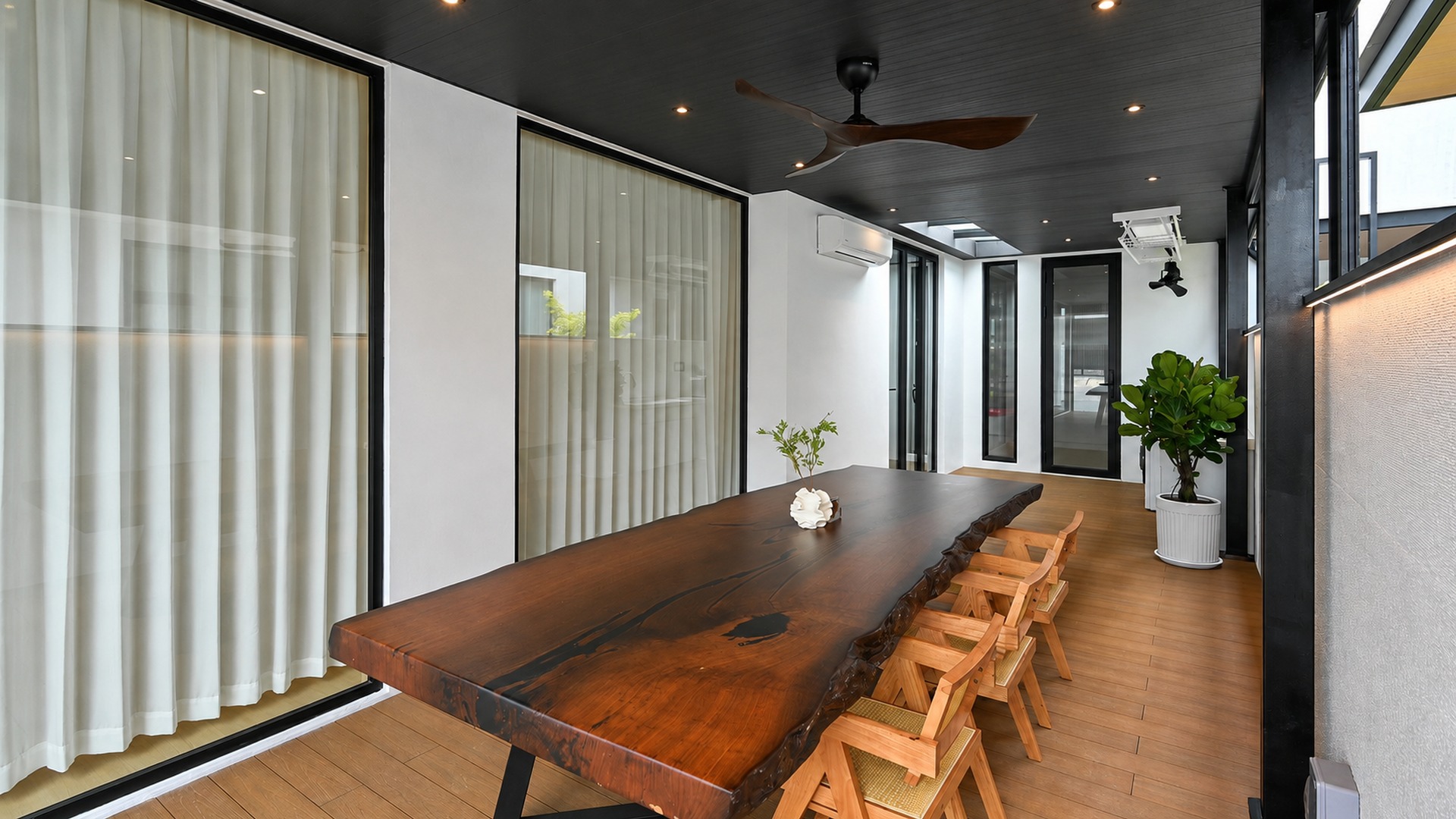 Sheltered outdoor dining area with a live-edge timber table in a Malaysian villa